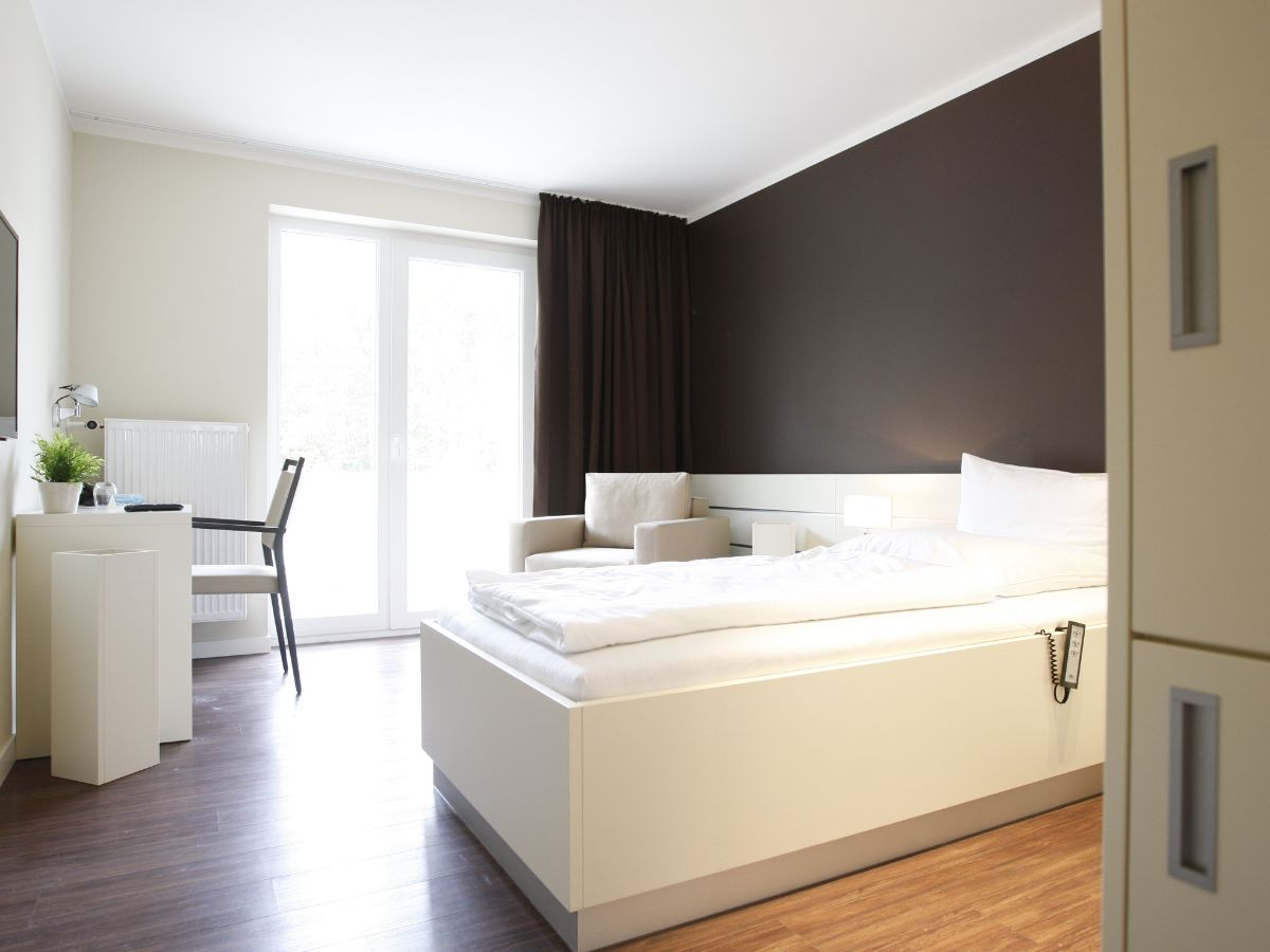 Komfortzimmer mit Einzelbett, Sessel, Tisch und Fernseher