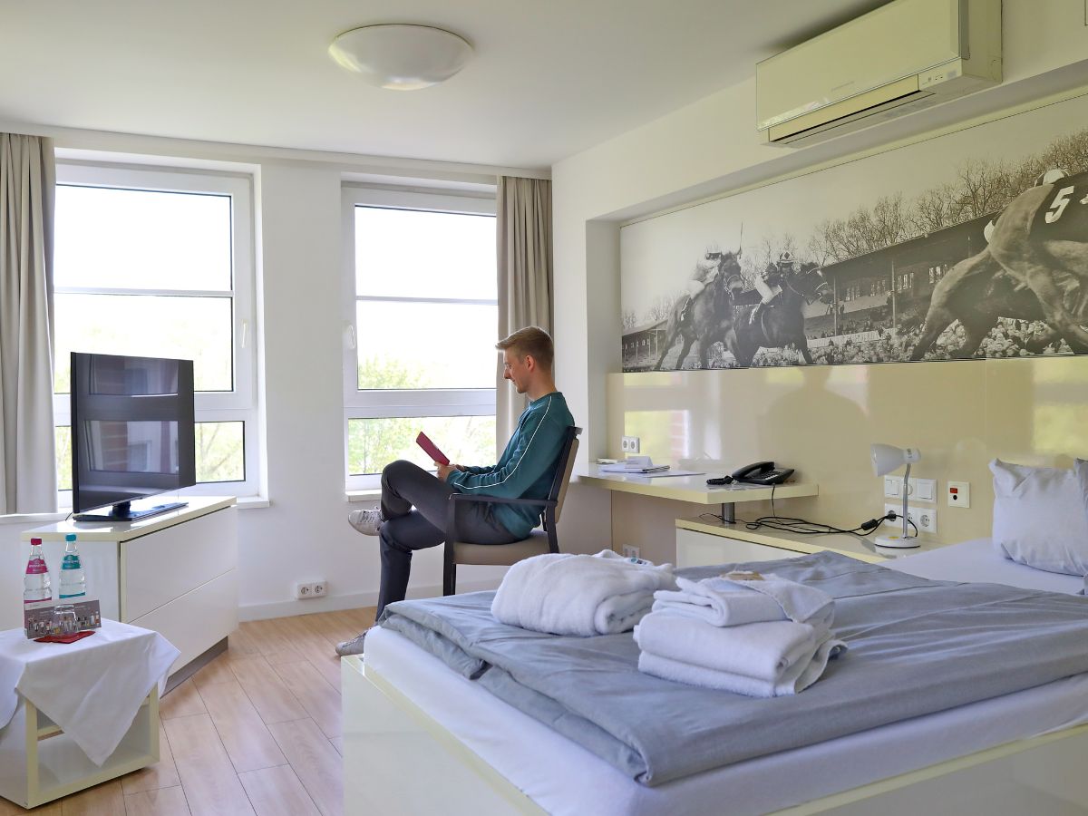 Ein Mann sitzt im Zimmer am Fenster und liest 