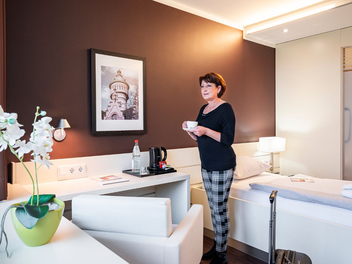 Eine Frau die mit ihrem Kaffee im Zimmer steht 